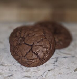 Close-up of two cracked chocolate cookies on a countertop.