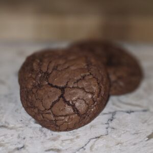 Close-up of two cracked chocolate cookies on a countertop.