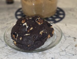 A large chocolate cookie with white chocolate chunks on a plate.
