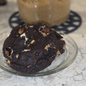 A large chocolate cookie with white chocolate chunks on a plate.