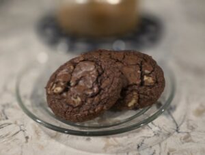 Two chocolate cookies on a glass plate.