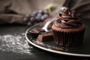 Chocolate cupcake with rich frosting and a brownie on a plate.
