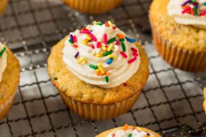 A vanilla cupcake with white frosting and colorful sprinkles.