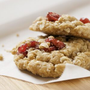 Close-up of oatmeal cookies with dried cranberries on parchment paper.