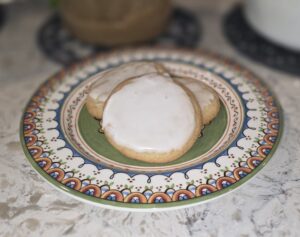 Two iced cookies on a decorative plate.
