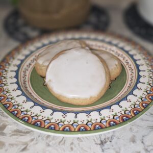 Two iced cookies on a decorative plate.