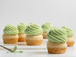 Vanilla cupcakes topped with green mint frosting on a white surface.