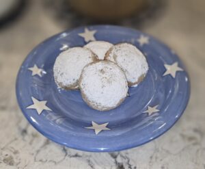 Three powdered sugar-coated cookies on a blue star-patterned plate.