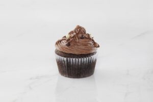 Chocolate cupcake with rich chocolate frosting and chocolate pieces on top.