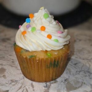 A vanilla cupcake with white frosting and colorful sprinkles.