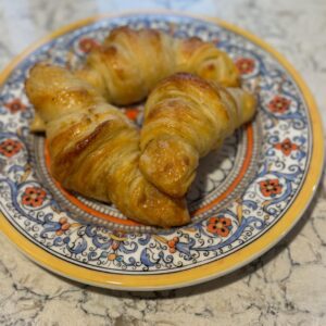 Two golden-brown croissants on a decorative plate.
