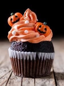 Chocolate cupcake with orange frosting and pumpkin decorations.